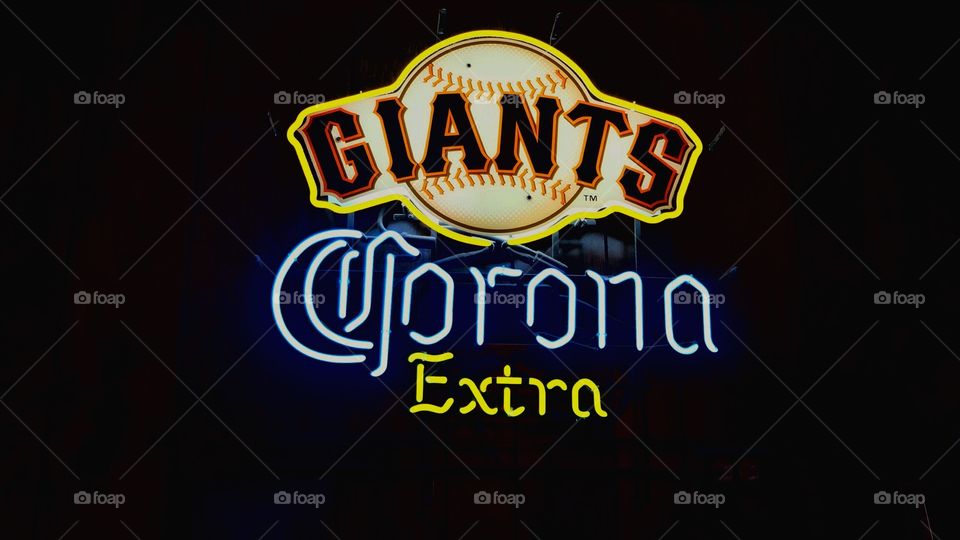 Neon Giants Corona Extra beer sign in a bar.