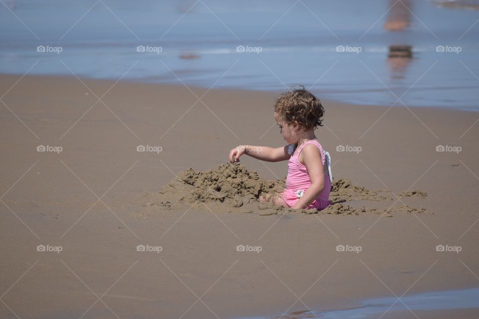 Playing in the Sand. A toddler girl playing in the sand at the beach.