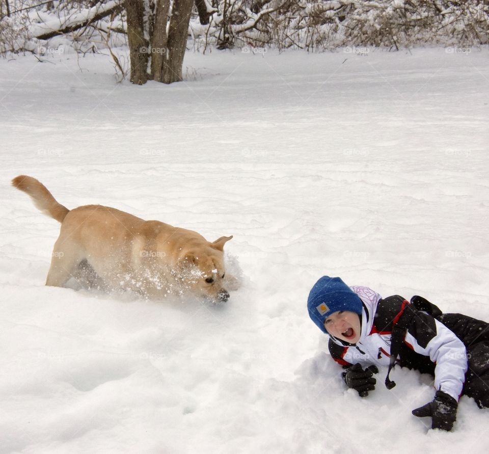 A boy and his dog playing in the snow 