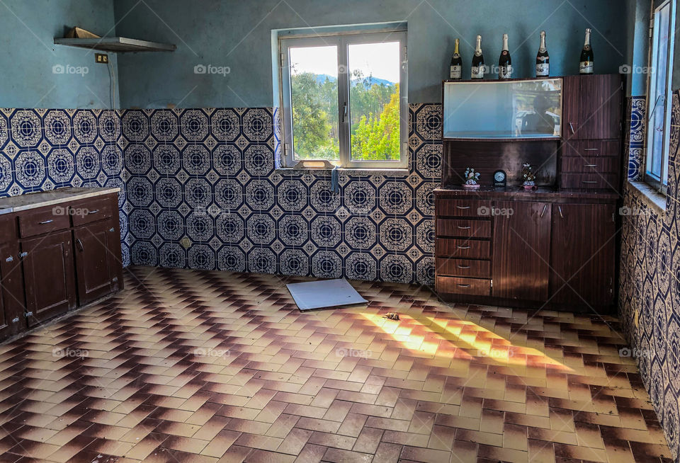 An old kitchen with the most horrendous tiling combination, there is a dated dresser with old bottles and the countryside can be seen through the window