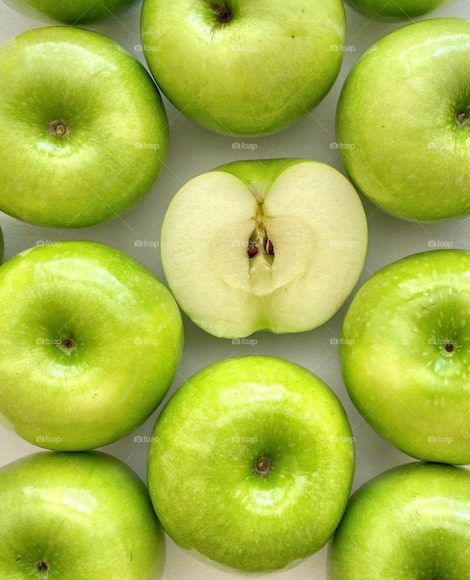 Granny Smith apples with one apple sliced in half