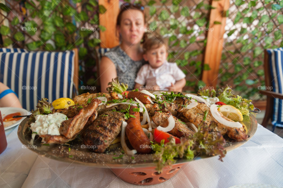 Traditional Greek meze plate full of variety of grilled meat on the table in restaurant.
