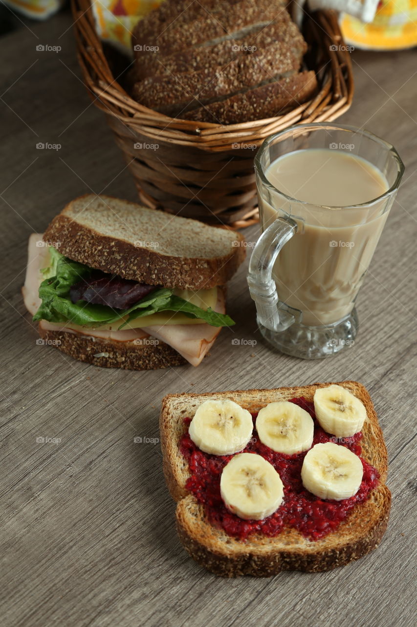tapa bread with marmalade and banana slices and a ham sandwich with bread slices in a basket