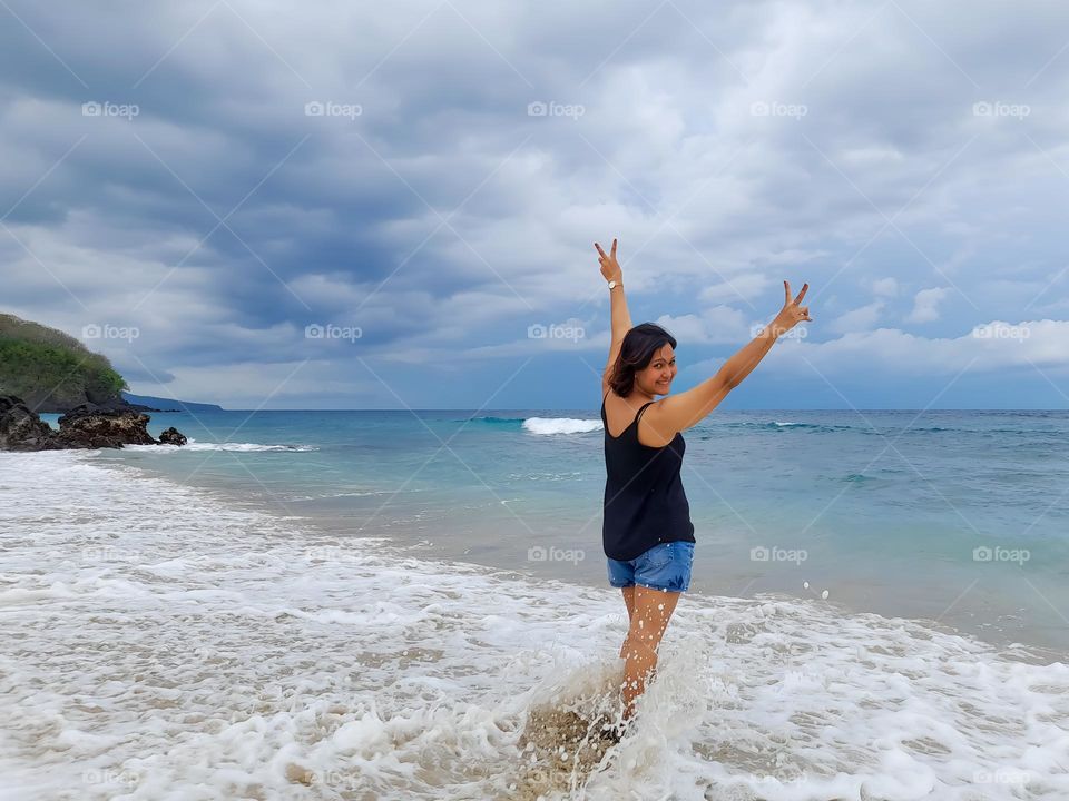 an asian woman is enjoying the small waves on the beach