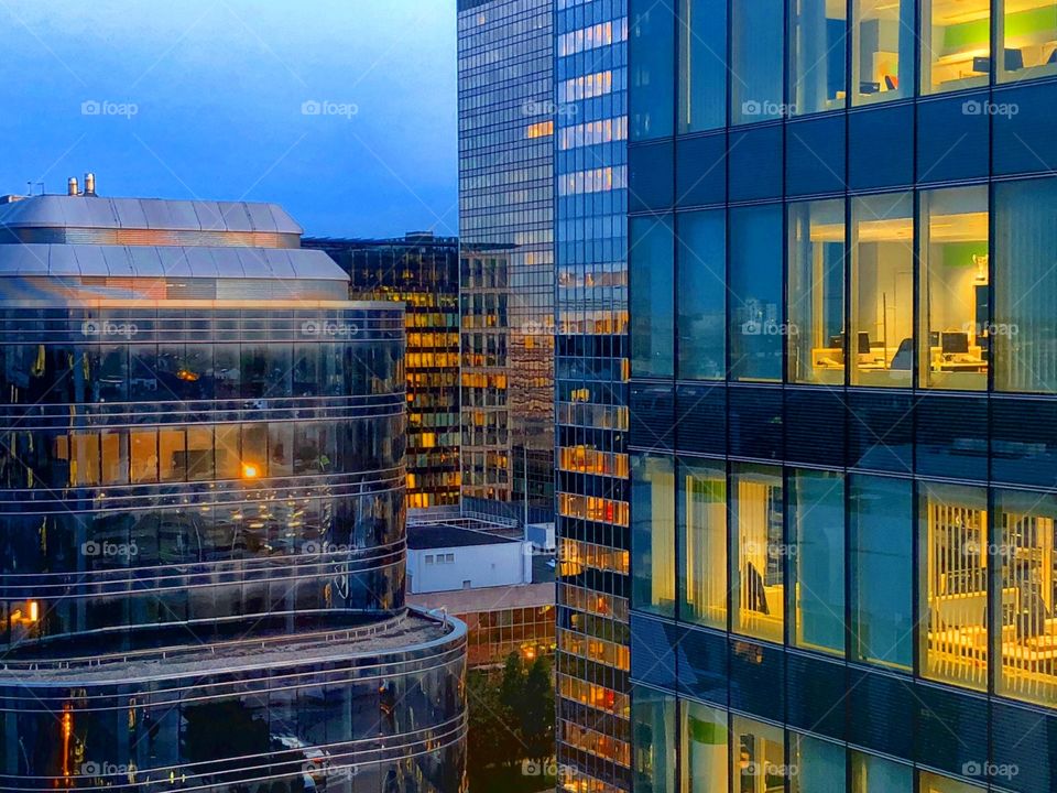 Different layers of business office windows at Dusk or dawn, showing lights in different rooms