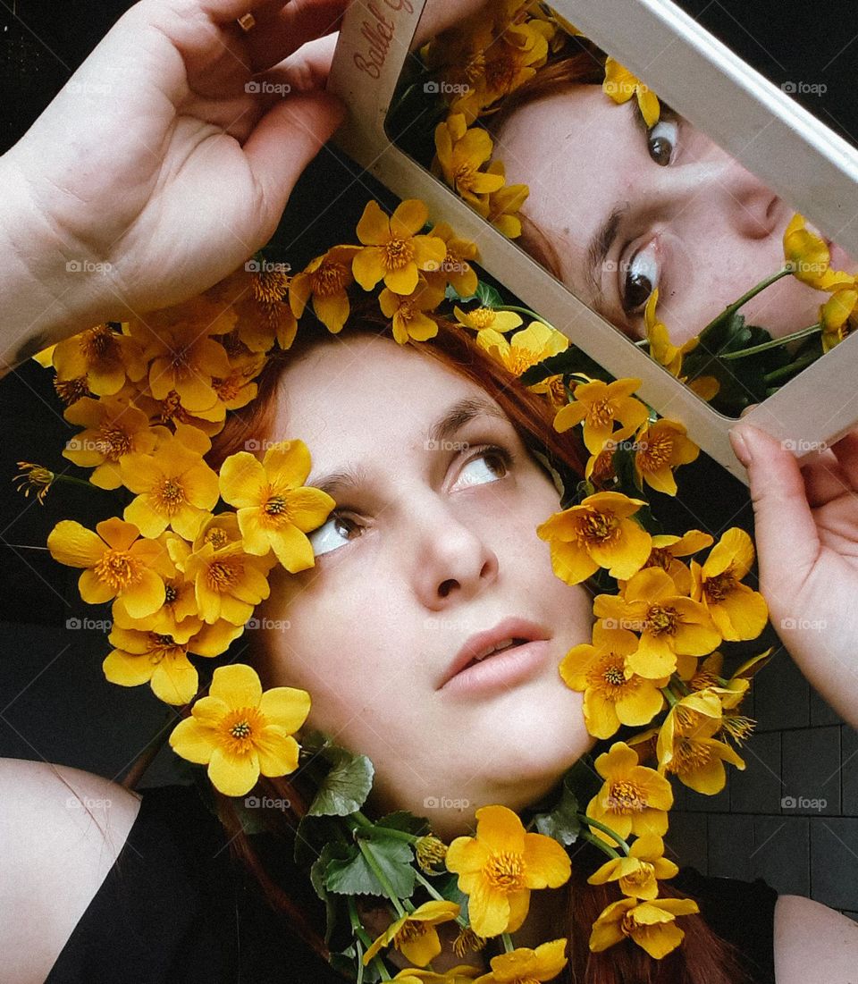 Photo of a portrait of a girl with yellow flowers in the mirror