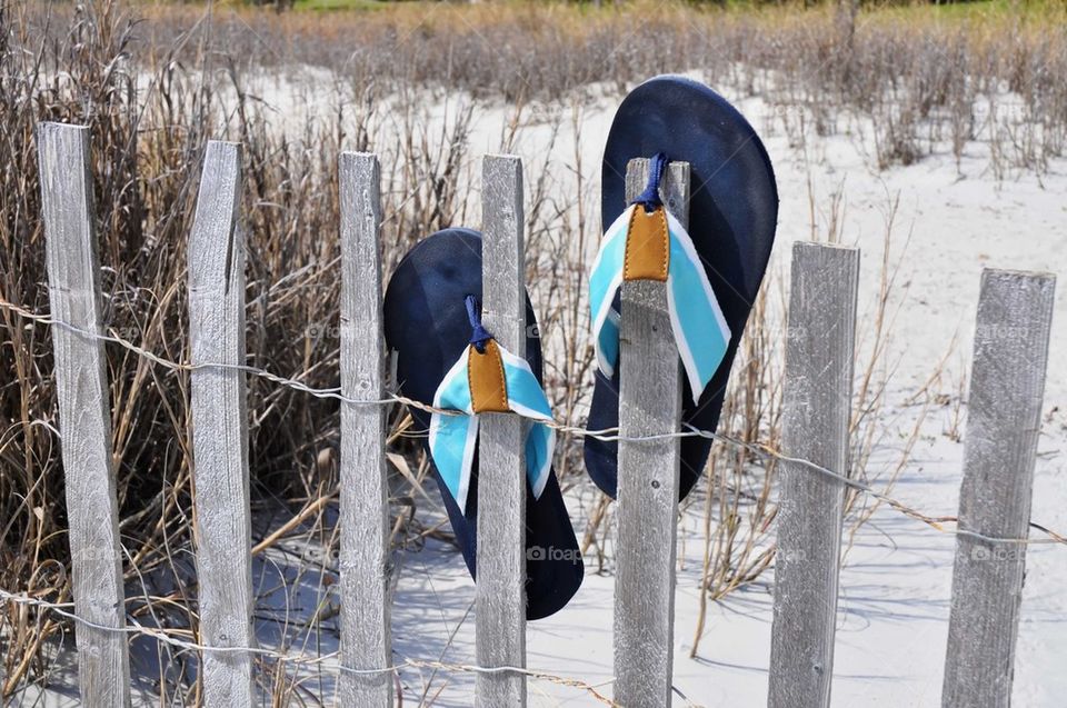 Flip-flops on a beach fence