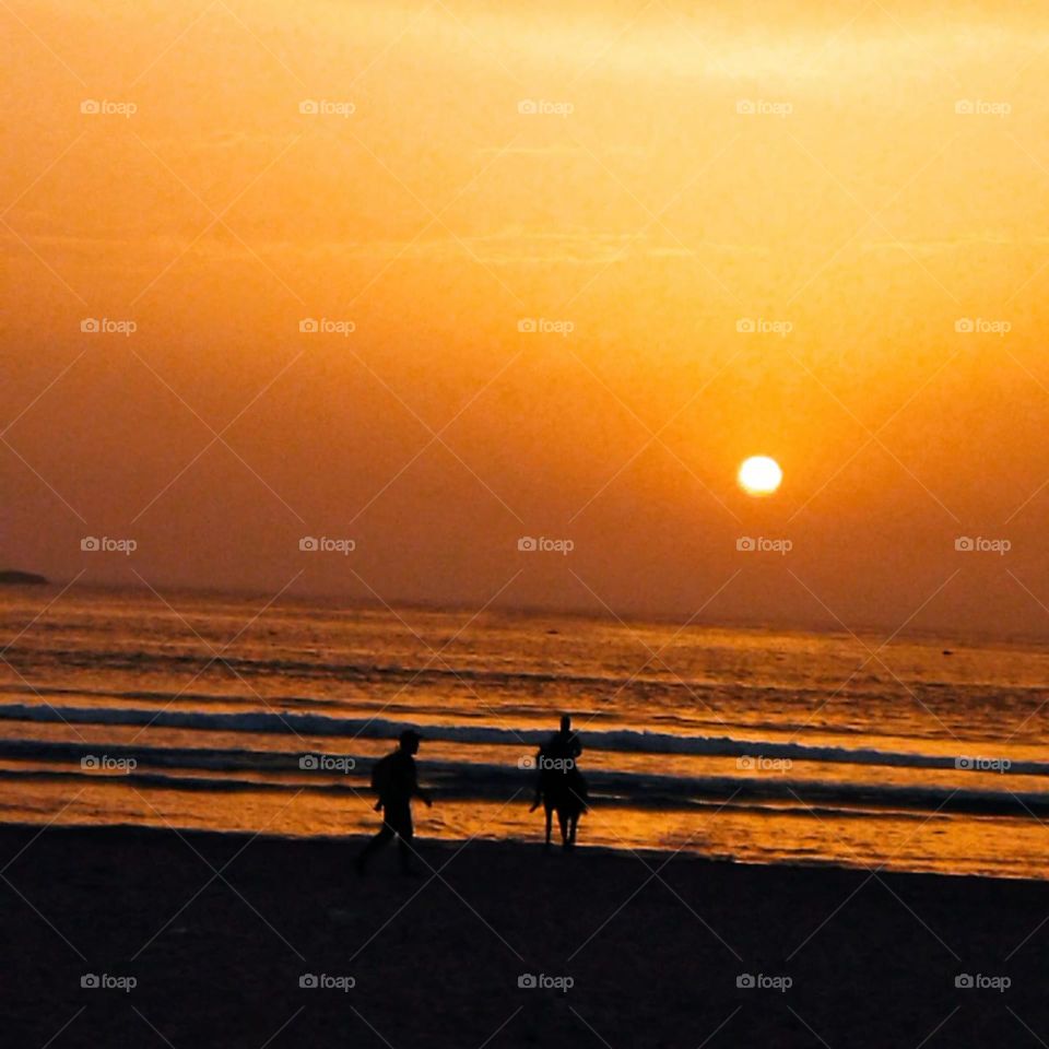 a boy and a young man on horseback near the beach watching the sunset.