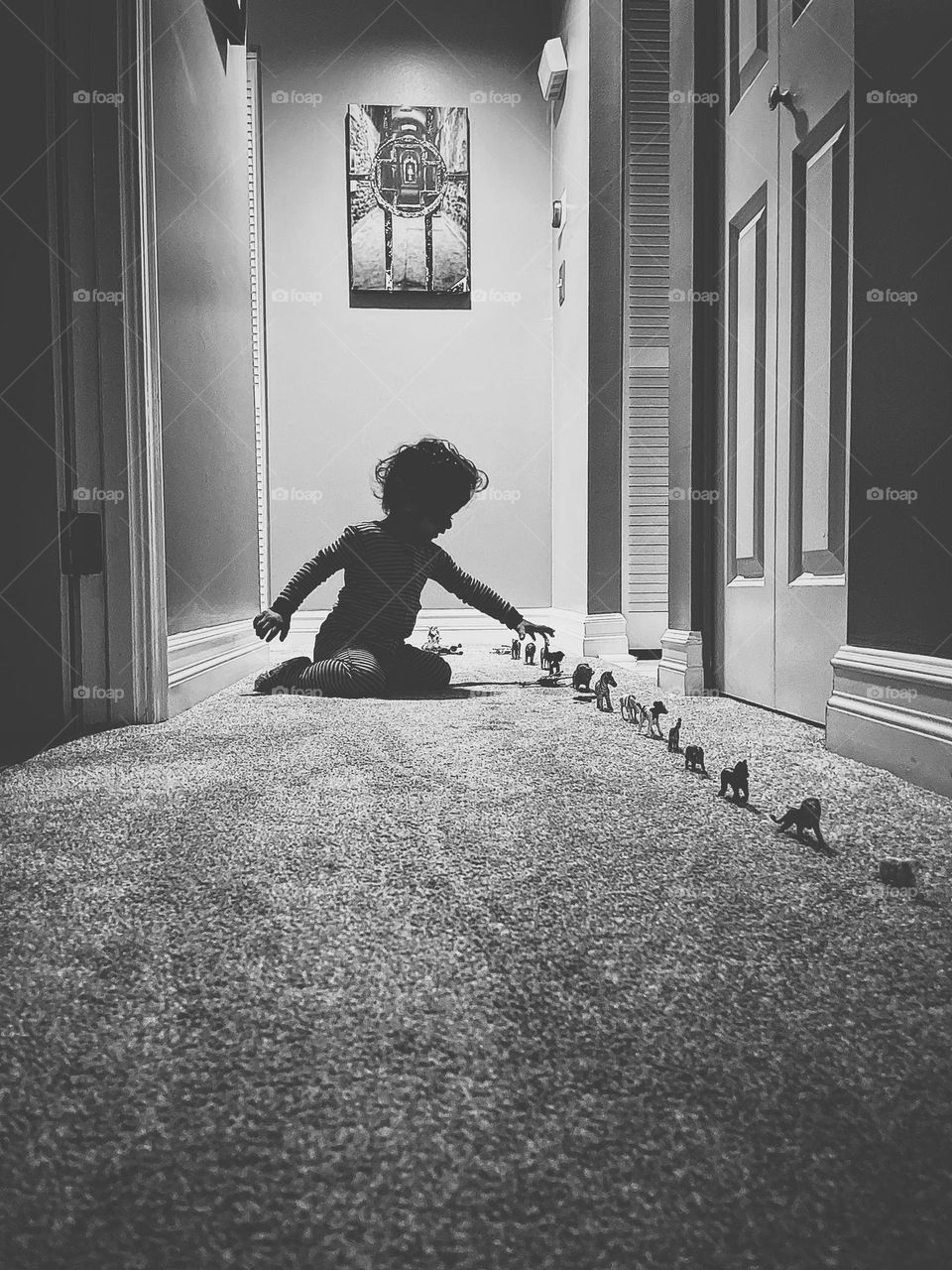 Child plays with train of animals leading to bedroom, black and white portraits of children playing, playing with little animal figurines 