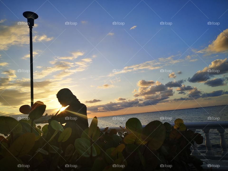 Beatiful and Amazing sunset in our paradise, cozumel Island, México. So lovely, with a pretty statue and a cruise ship on the ocean. The most Beatiful sunsets are in this big Island in the mexican caribbean.
