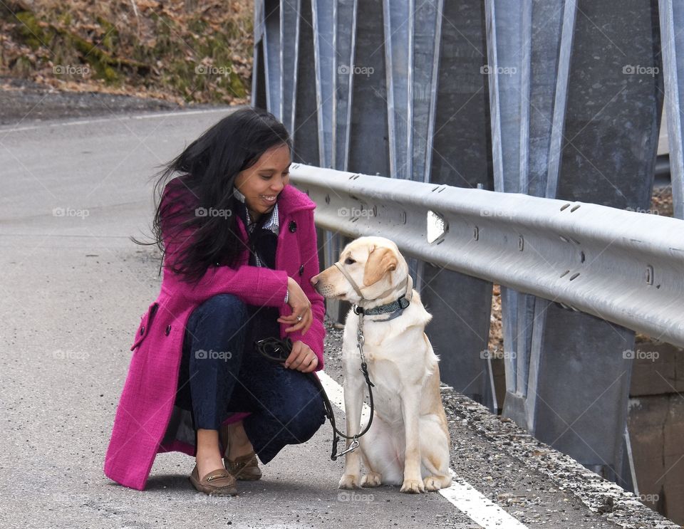 Puppy Love,young lady in a pink coat looking at her yellow Labrador 