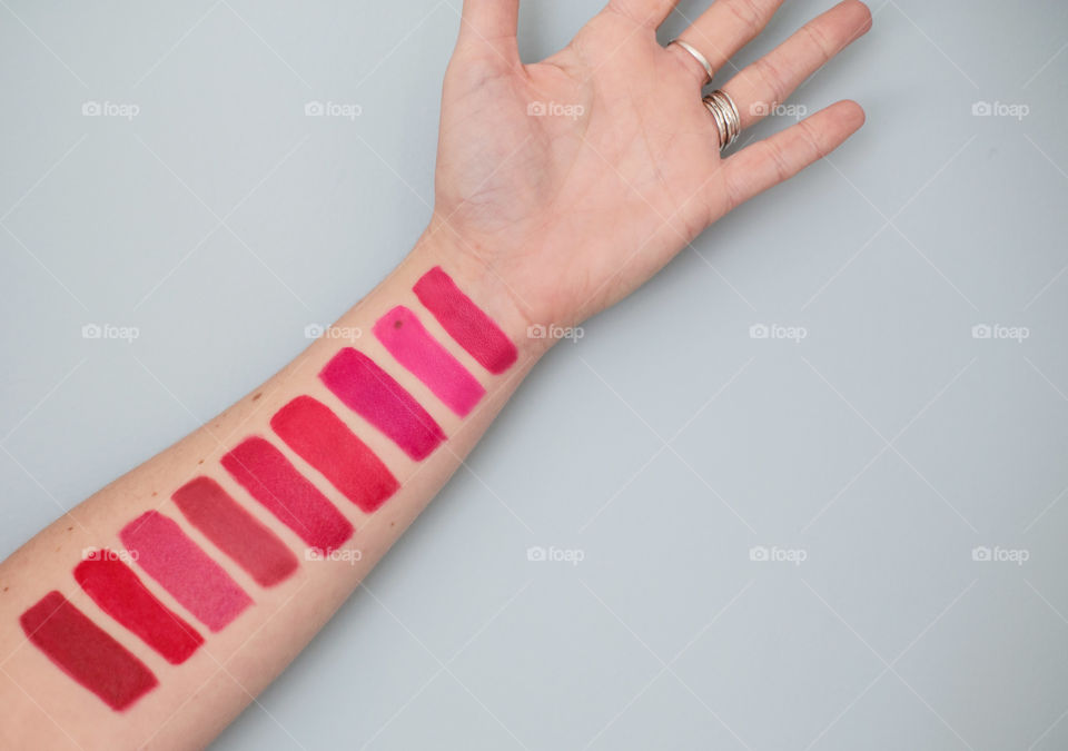 Bright red and pink lipstick stripes on my arm showing negative space and vibrant color. 