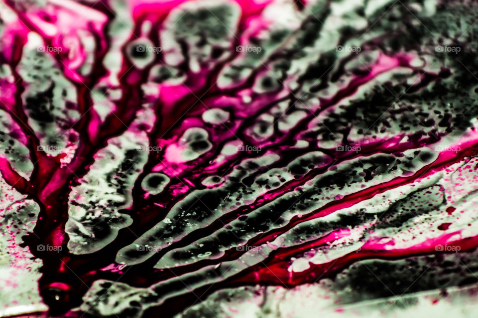 Black and pink refill ink spilled onto the white sink and the ink mixed into abstract blobs and patterns.