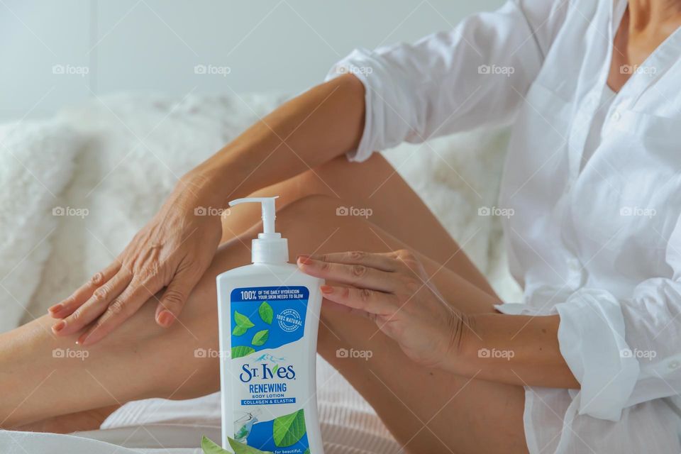 Woman applying Body Lotion on her legs 