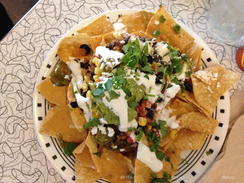 Nachos Supreme -made with our original recipe cashew-based nacho cheese and topped with quinoa, black beans, black olives, cilantro, corn, tomatoes, green onions, sour cream, guacamole & pickled jalapenos. At the Spiral Diner in Dallas