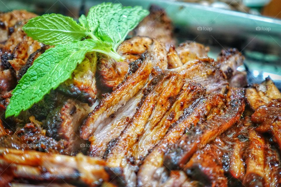 Barbecue (BBQ) marinated beef brisket sliced into thin portions. Garnished with a sprig of fresh mint. Succulent, full of flavor and melts in the mouth. A perfect addition to any family roast.