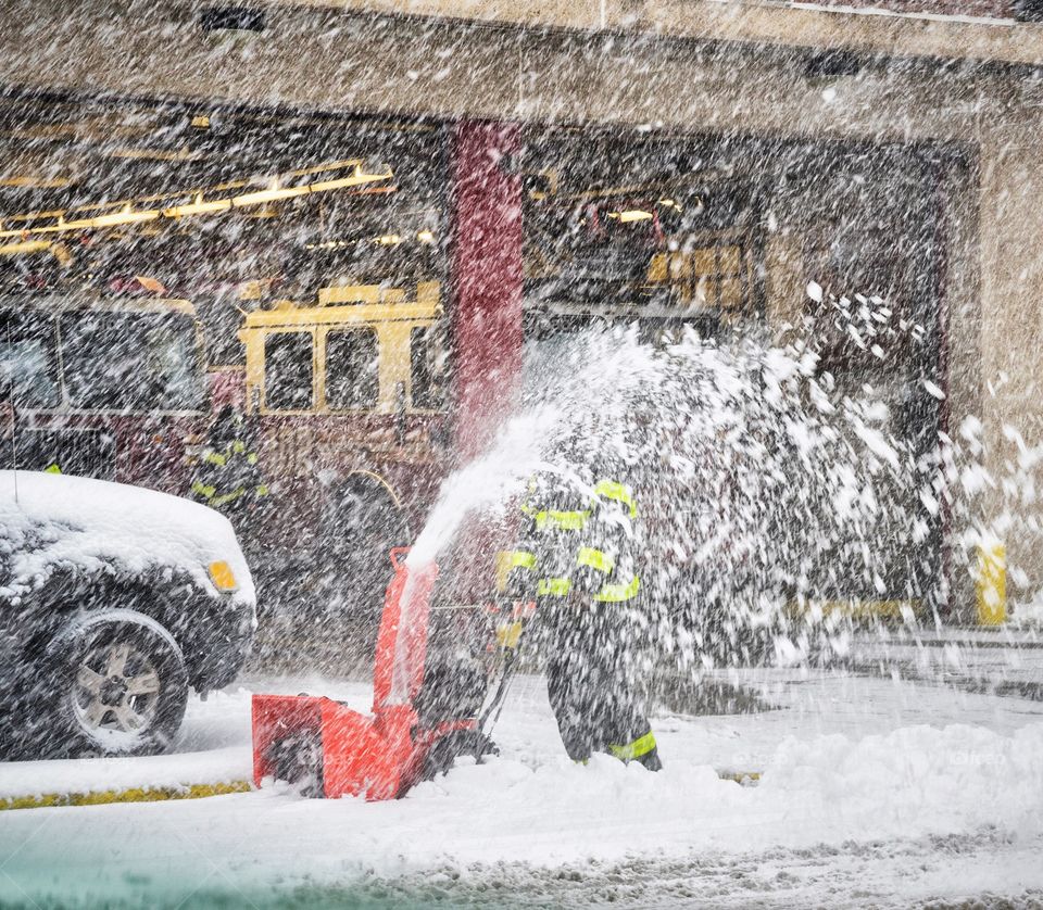 A fire fighter blowing the snow at his station 
