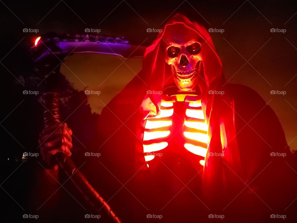 Spooky Animatronics skeleton with glowing red coming out of his chest.  Displayed outdoors for Halloween by an avid animatronics collector.