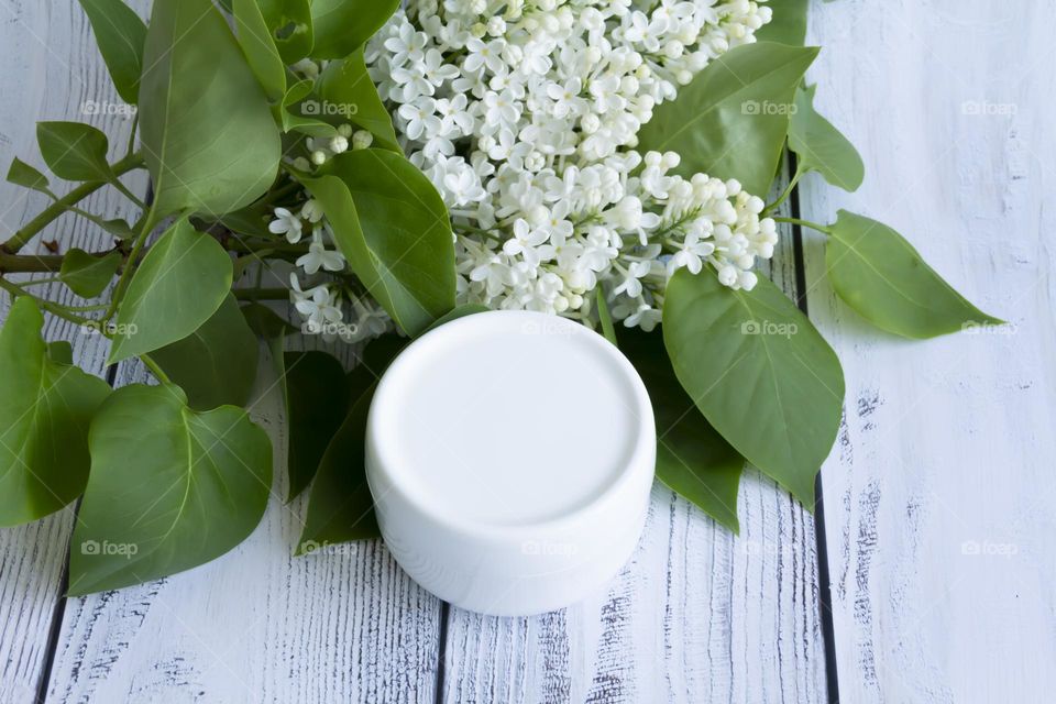 Spring, white fragrant lilac with green leaves.  and jars with cosmetic cream and product.