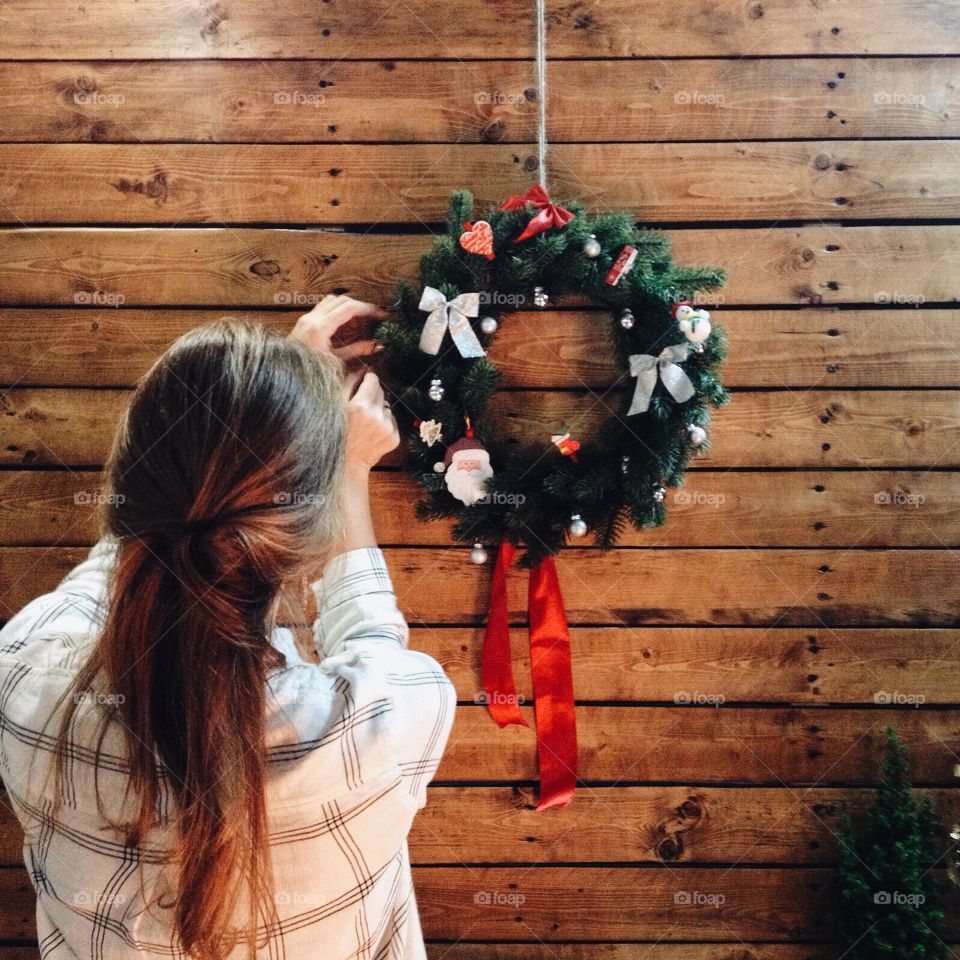 Girl decorating a Christmas wreath on a wooden wall