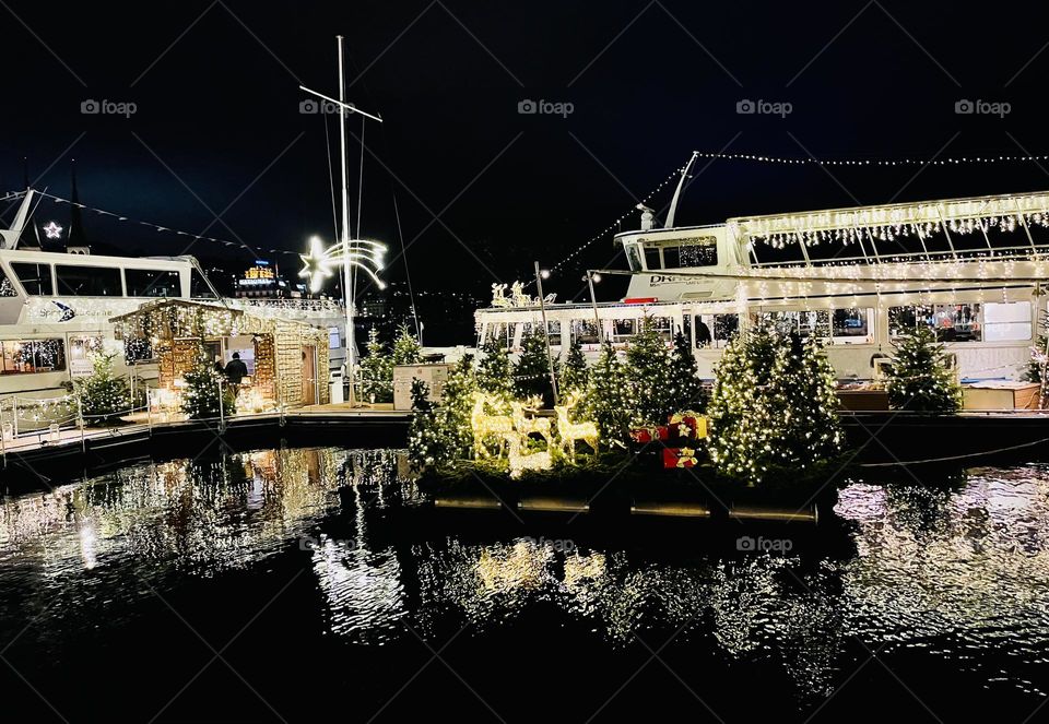 Christmas decorated boats at Lucerna Switzerland lake with lights reflecting on the water 