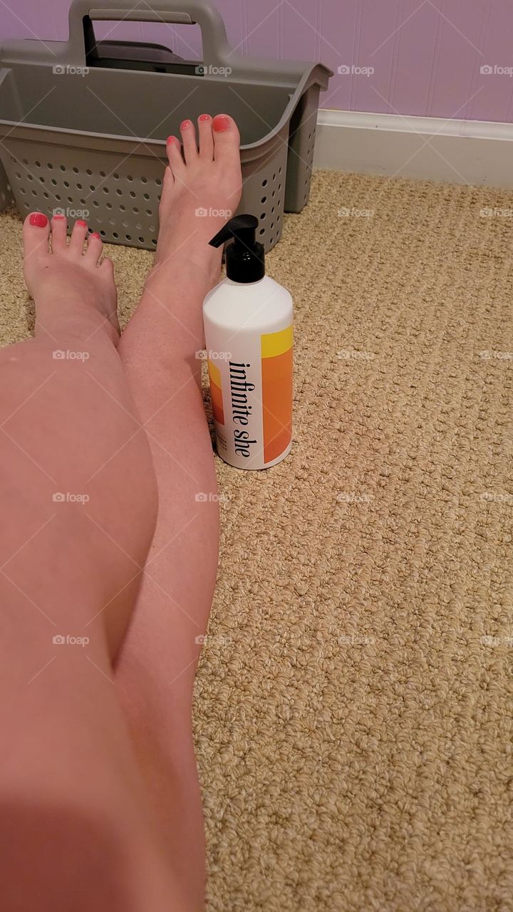 infinite she empowered hydrating body lotion by Margot Elena next to long legs and painted toes