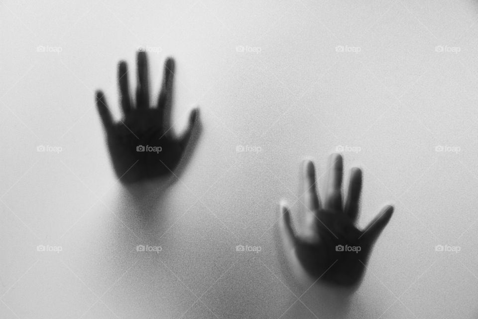 Shadow hands of the Man behind frosted glass.Blurry hand abstraction.Halloween background.Black and white picture