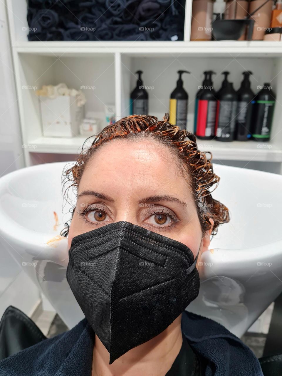 woman with ffp2 anti covid mask waiting to wash dyed hair at the hairdresser