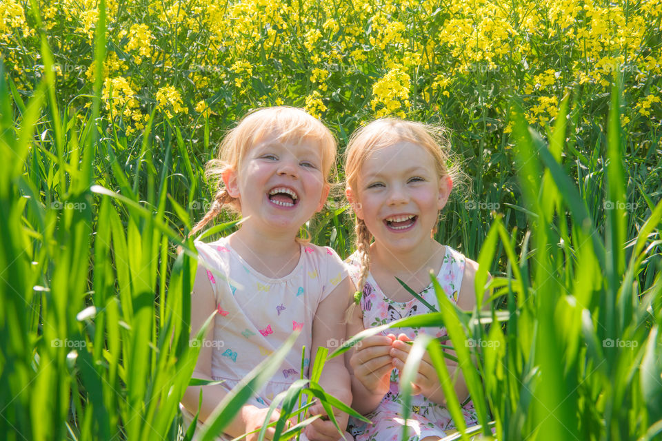 Happy sister sitting in field laughing