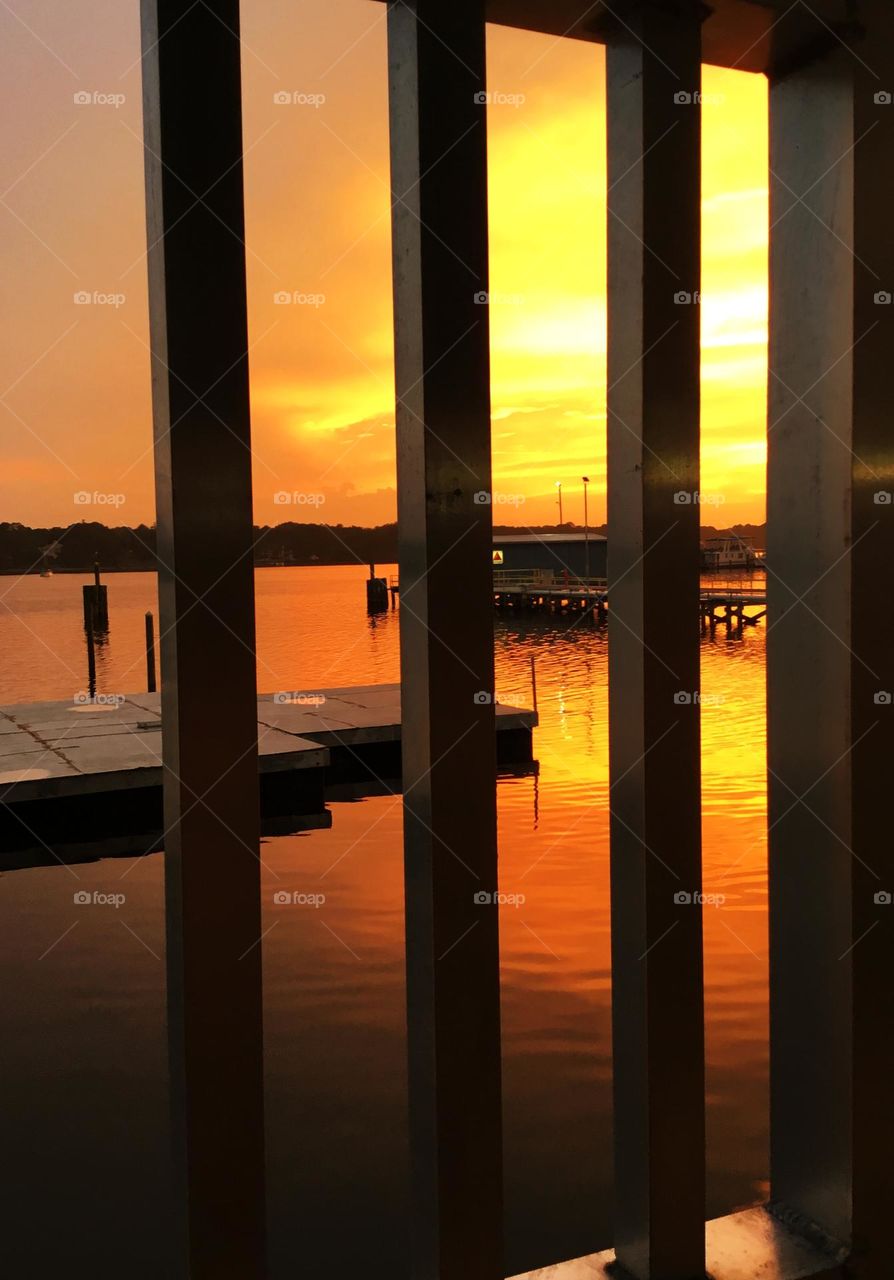 A shimmering, descending sunset shows its radiant reflection through the steel bars