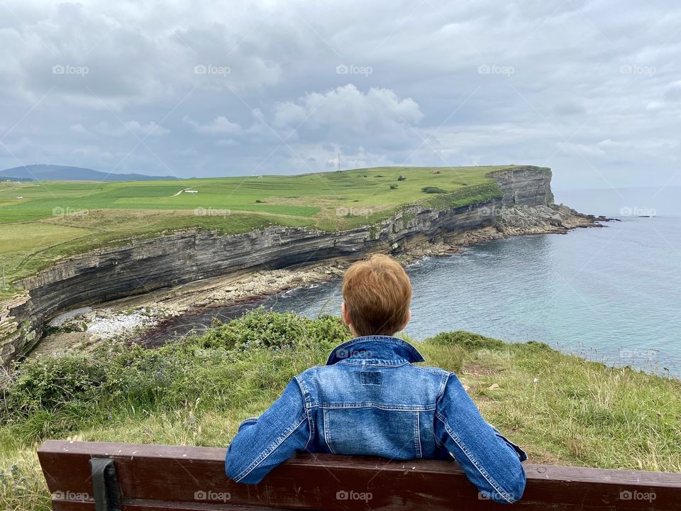 Woman sitting on a bench in front of the cliffs
