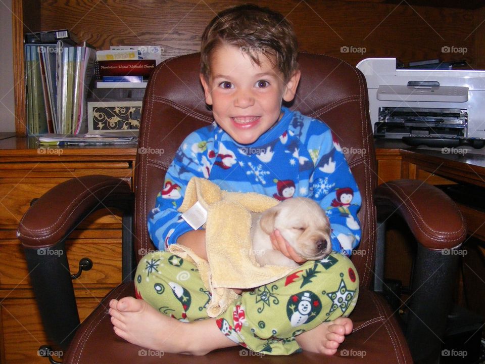 Happy boy sitting on chair with cute puppy