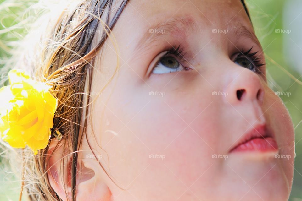 Gorgeous photo of young girl looking up at the sun with a yellow flower in her hair!! 