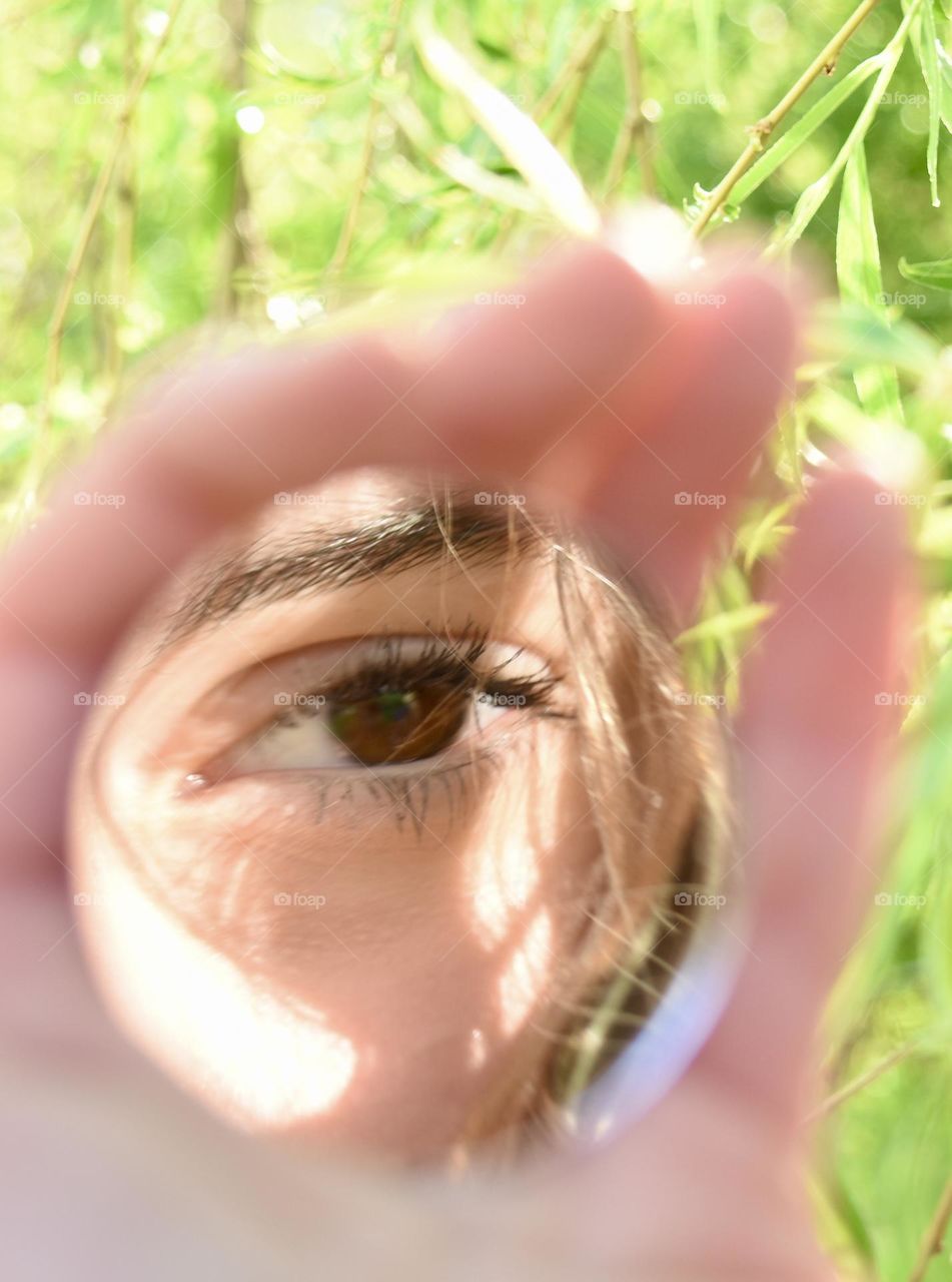 Girl holding small mirror with reflection of her eye
