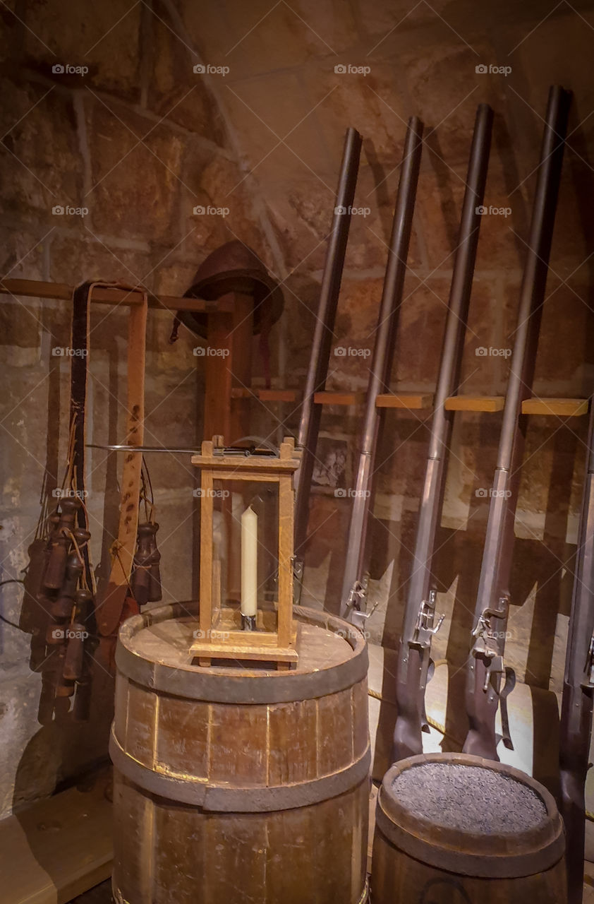 The historic interior of the armory.  Barrel with a lamp with a candle, an ancient weapon against a stone wall