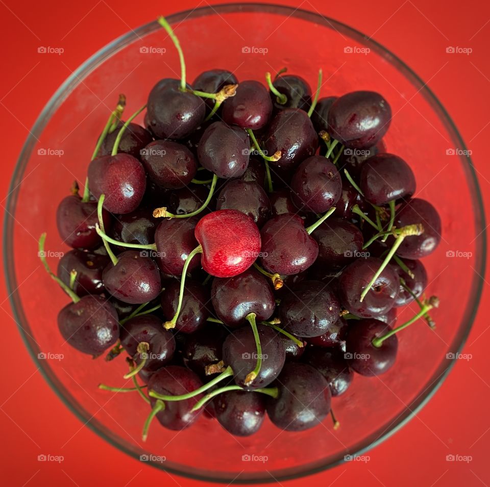 A bowl of cherries on a red table