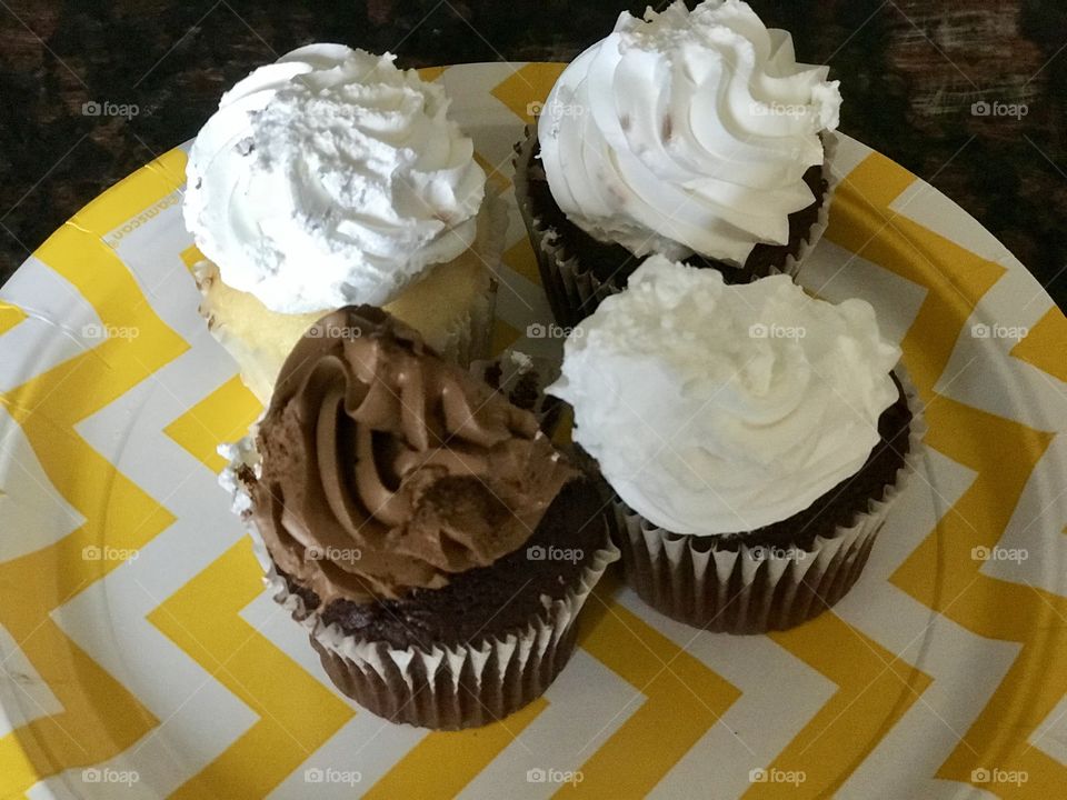 Delicious chocolate and vanilla birthday cupcakes on a bright yellow and white paper party plate . USA, America 