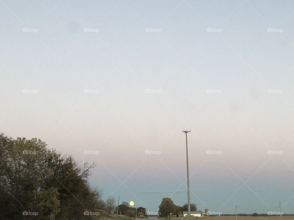 Rural photo with moon sitting at the horizon