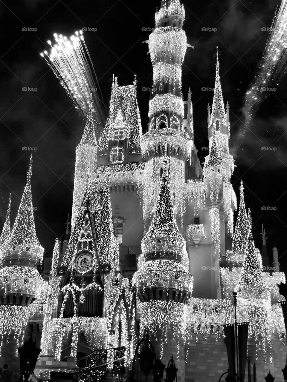 Black and white Magic Kingdom Cinderella’s Castle with winter icesicle lights and fireworks going off 