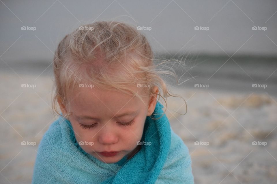 Cold girl at the beach. Toddler getting warm in a towel