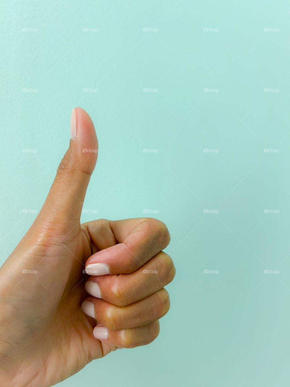 Thumbs up against light blue background