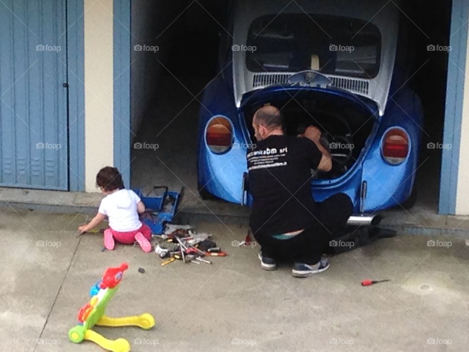 Man looking at her daughter while repairing car