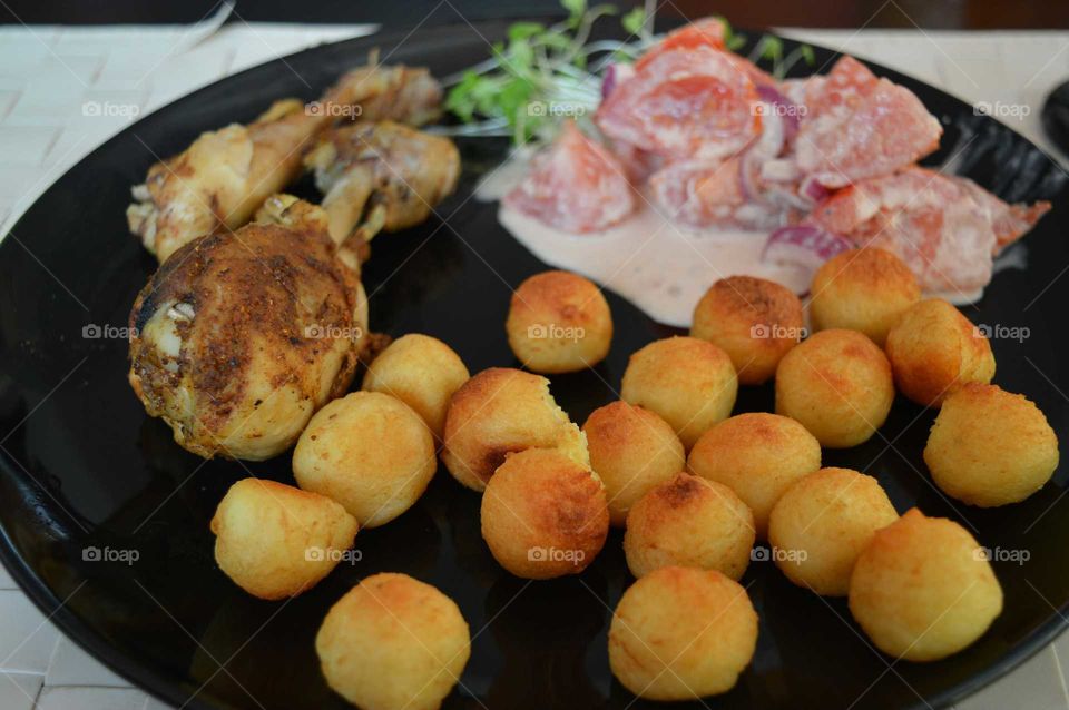 A delicious dish. Chicken legs with baked potato balls and salad with fresh tomatoes ,cress and onion.