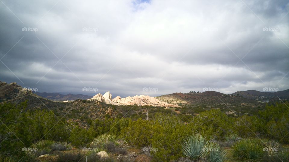 Grassy land against cloudy sky