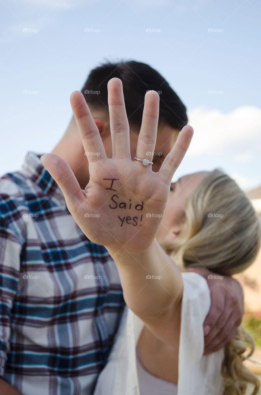 Couple kissing while woman showing text written on her hand