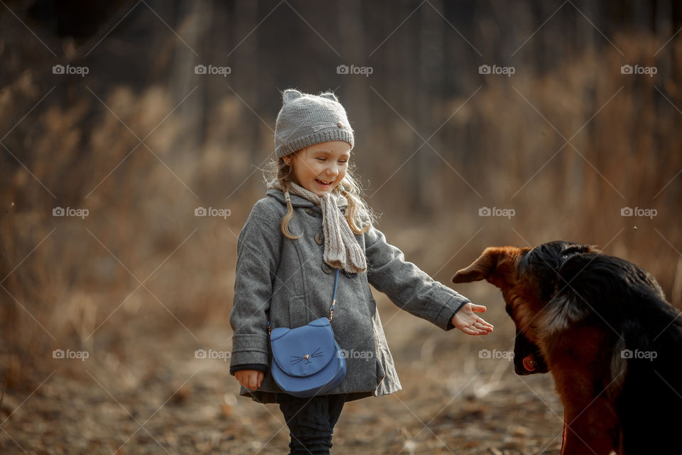 Little girl with German shepherd young male dog walking outdoor at spring day