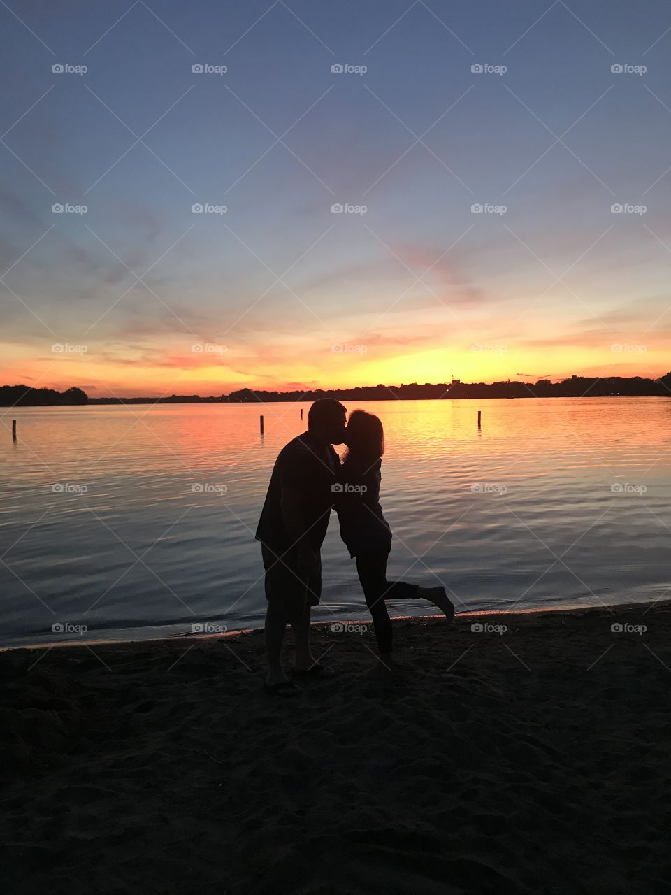 Gorgeous night sky in background and couple silhouetted kissing by the lake! 