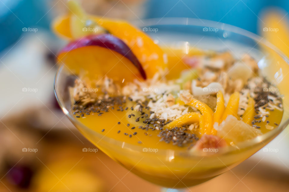 Yellow fruit smoothie bowl with mango, nectarine, coconut, ginger, granola clusters and chia seed 