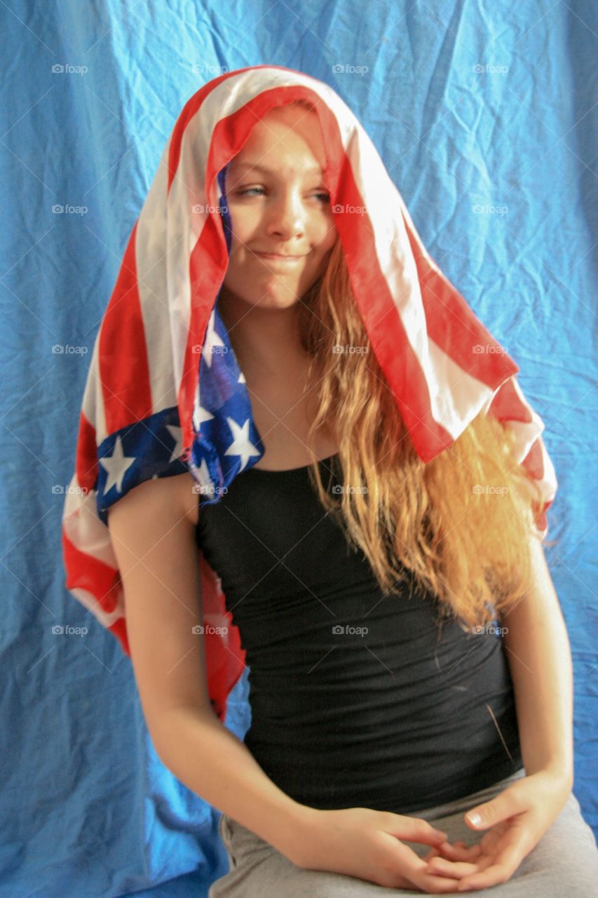 Teenage girl making funny faces while showing off the American flag