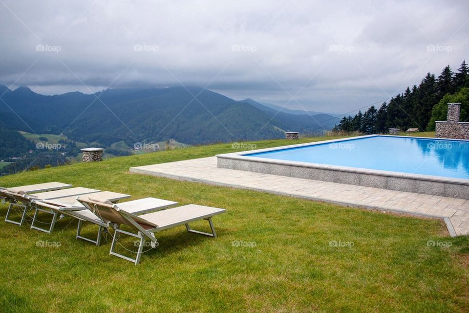 Empty lounge chair in front of swimming pool